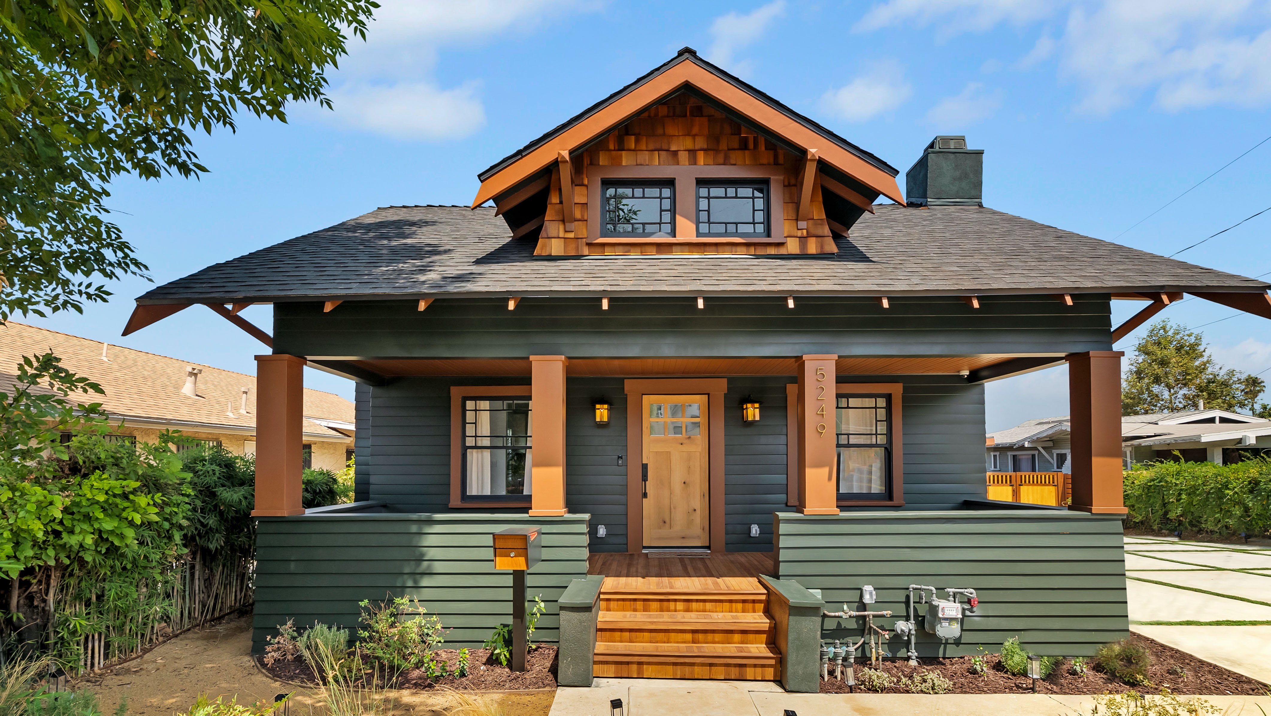 Green Craftsman-style home with wood accents and front porch.