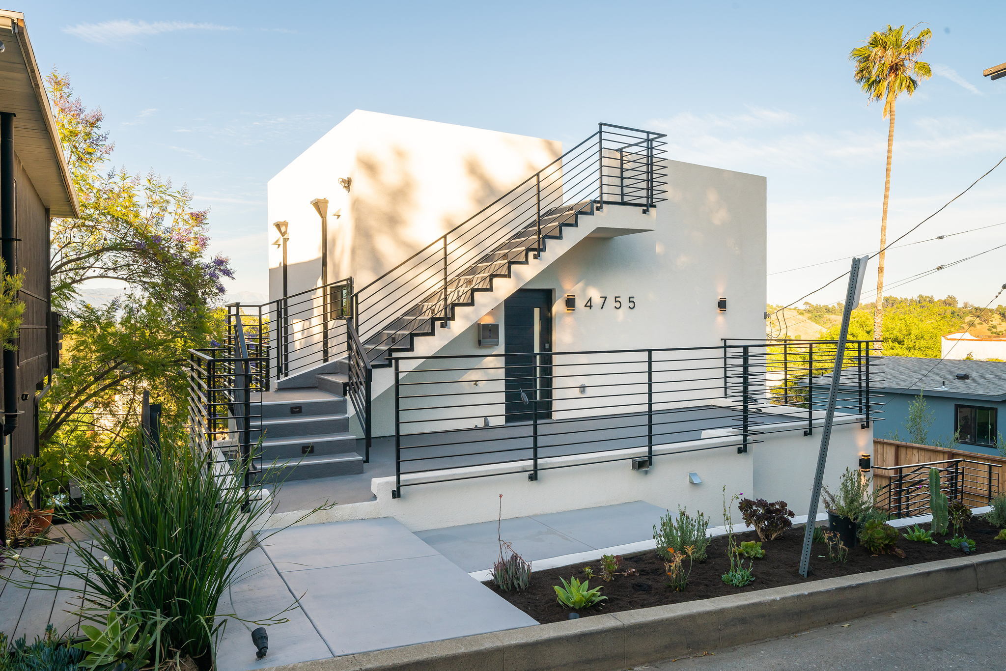 Modern multifamily building with exterior staircase and clean white façade.