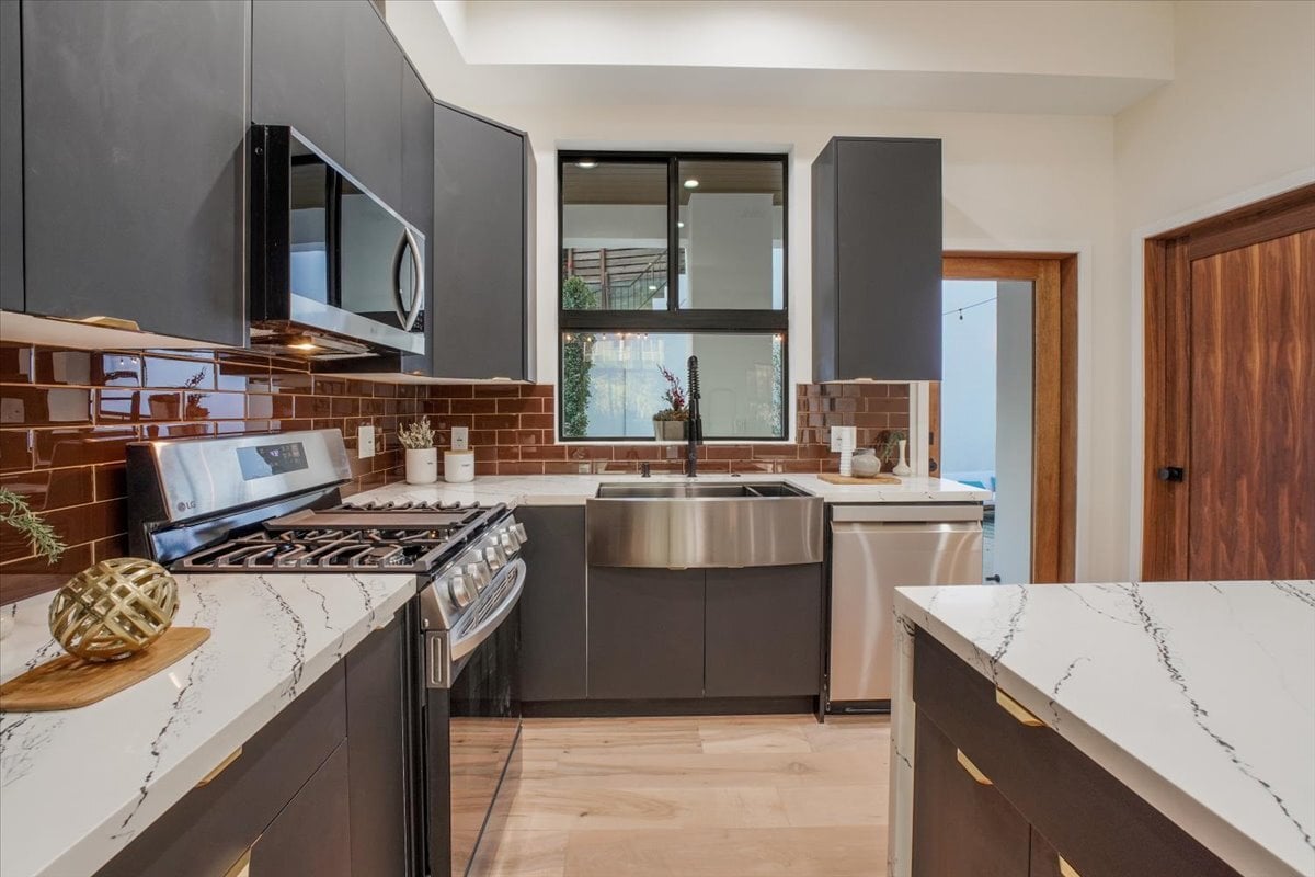 Contemporary kitchen with gray cabinets, stainless steel appliances, and tile backsplash.