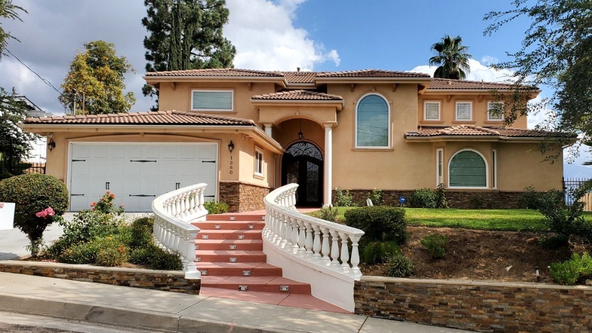 Mediterranean-style two-story home with stucco exterior, arched entryway, and curved staircase