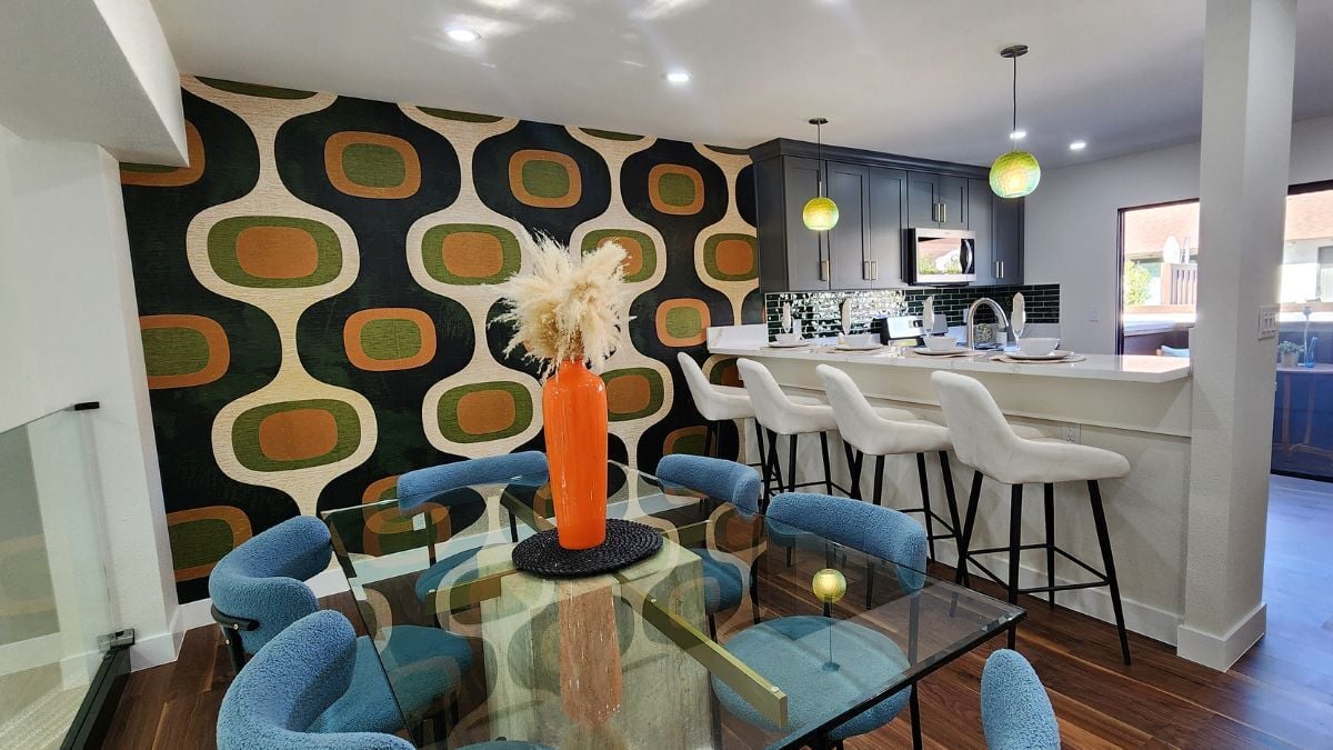 Mid-century inspired dining and kitchen area with bold retro wallpaper, modern lighting, and open-concept interior design