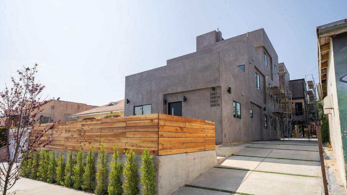 Modern apartment building with concrete facade, wood fencing, and minimalist residential architecture