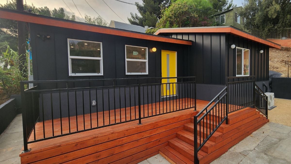 Modern black bungalow remodel with wood deck, railing, and contemporary exterior renovation