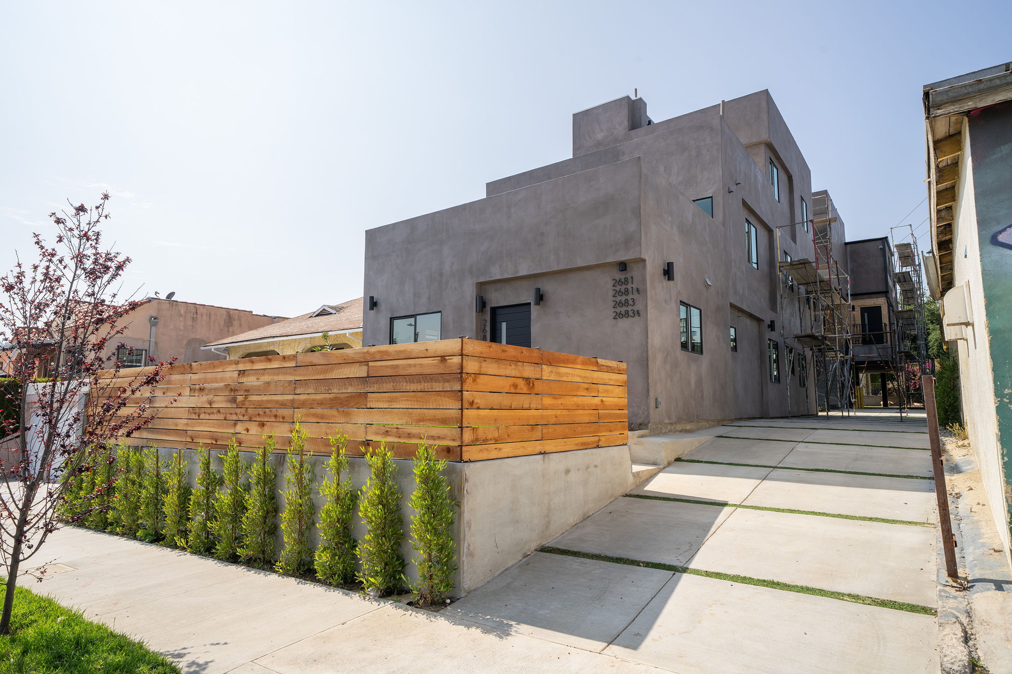 Contemporary stucco multifamily building with wood fencing and clean modern lines.