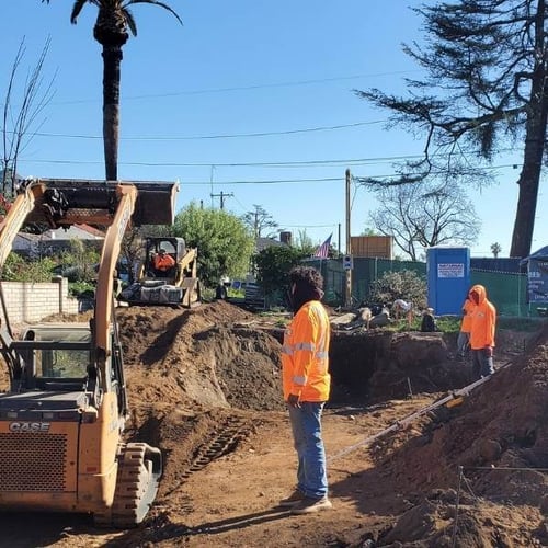 Excavation work underway for a residential rebuild in Altadena, with construction crew and excavator preparing the foundation.