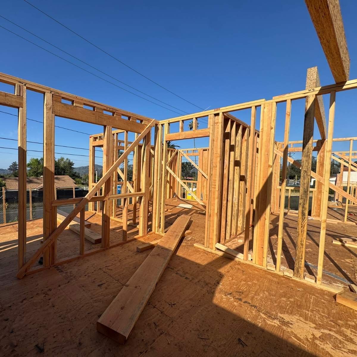 Interior wood stud framing of a residential home under construction by ATP Development & Construction showing wall and door frame layout against a clear blue sky in the Altadena area