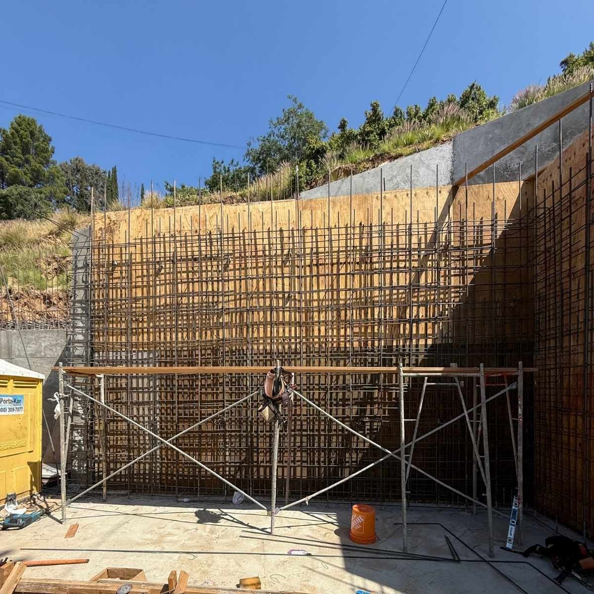 Large-scale retaining wall rebar reinforcement grid on scaffolding along an excavated hillside by ATP Development & Construction in the Los Angeles area