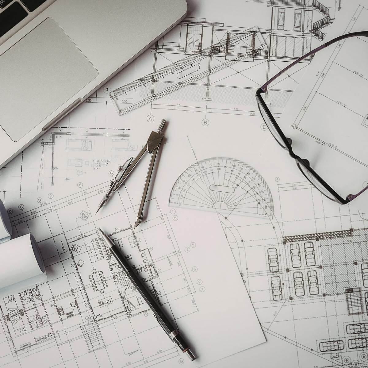 Close-up of a precision drafting compass on detailed structural engineering drawings with technical measurements, representing ATP Development & Construction's structural engineering expertise in Los Angeles
